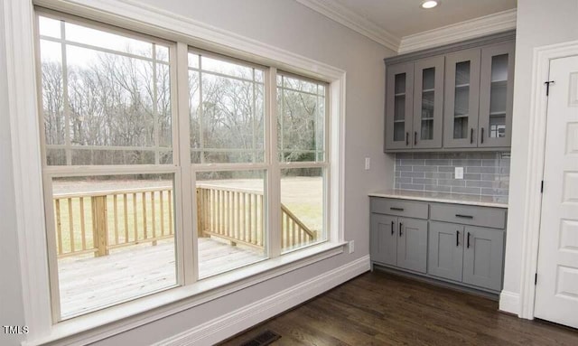 unfurnished dining area with dark hardwood / wood-style floors, a wealth of natural light, and ornamental molding