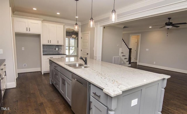 kitchen with stainless steel dishwasher, white cabinetry, sink, and an island with sink