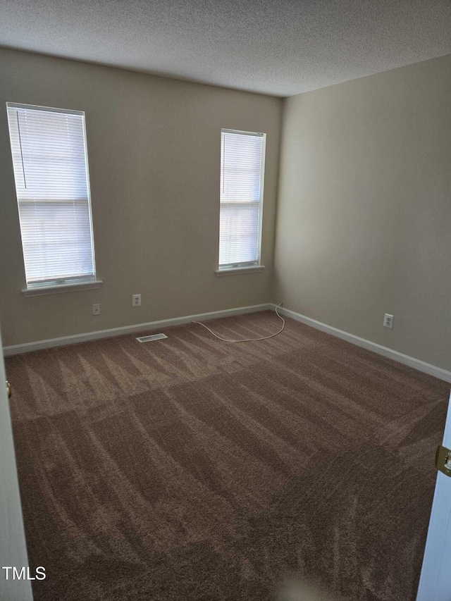 carpeted spare room with a textured ceiling