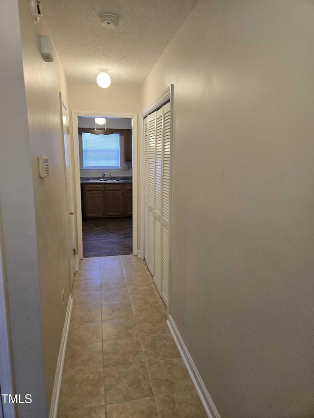 hall featuring a textured ceiling and tile patterned floors