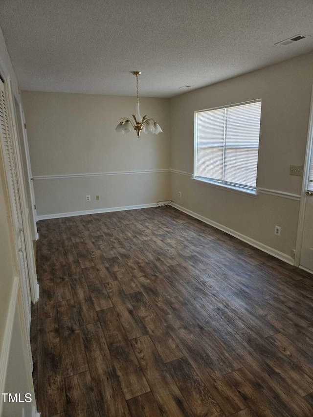 unfurnished dining area featuring a textured ceiling, dark hardwood / wood-style floors, and a notable chandelier