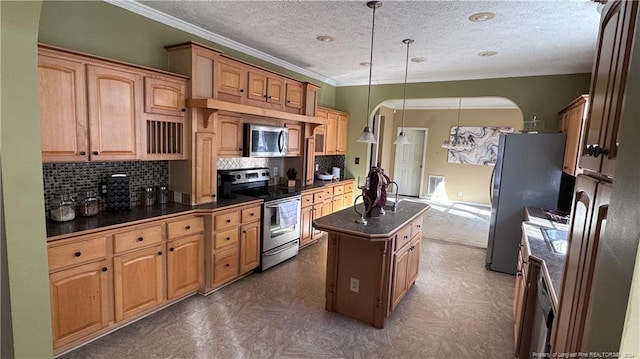 kitchen featuring a kitchen island with sink, crown molding, tasteful backsplash, decorative light fixtures, and stainless steel appliances