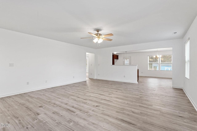 unfurnished living room with ceiling fan with notable chandelier and light wood-type flooring