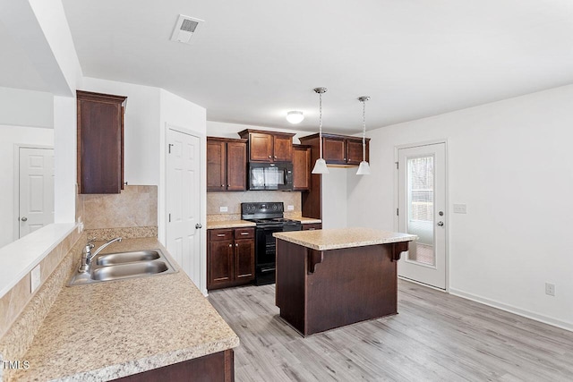 kitchen featuring pendant lighting, black appliances, sink, decorative backsplash, and light hardwood / wood-style floors