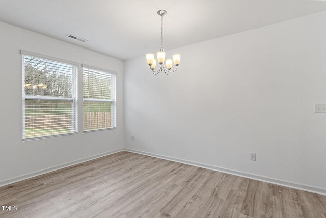 unfurnished room featuring light hardwood / wood-style flooring and an inviting chandelier