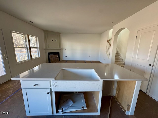 kitchen featuring white cabinetry, a kitchen island with sink, and a fireplace