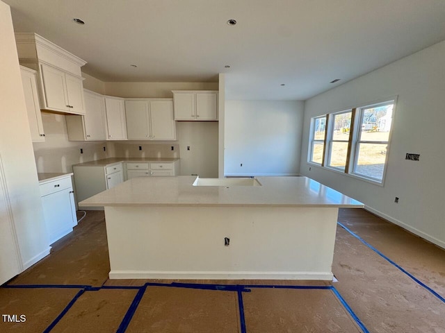 kitchen featuring white cabinets and an island with sink