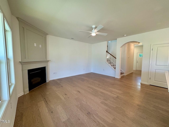 45 Covey Rise Way, Lillington, NC 27546 - unfurnished living room featuring arched walkways, ceiling fan, wood finished floors, stairway, and a fireplace