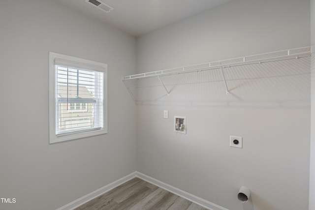 clothes washing area with electric dryer hookup, washer hookup, and hardwood / wood-style flooring