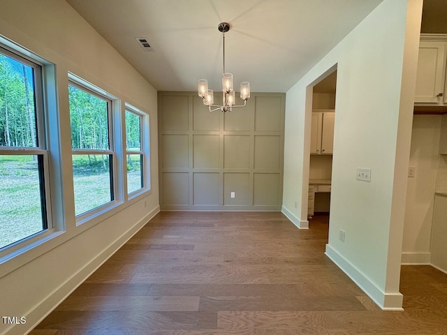 262 Grand Griffon Way, Lillington, NC 27546 - unfurnished dining area featuring wood finished floors, a decorative wall, and a chandelier