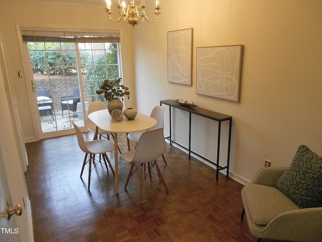 dining space with dark parquet floors and a chandelier