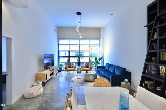 living room featuring a high ceiling, concrete floors, and baseboards