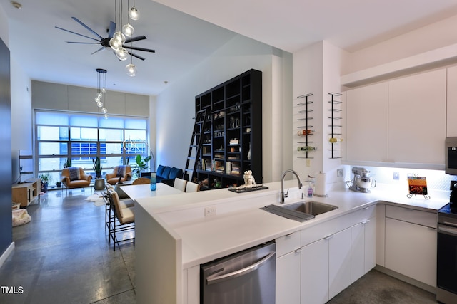 kitchen featuring kitchen peninsula, decorative light fixtures, stainless steel dishwasher, white cabinets, and sink