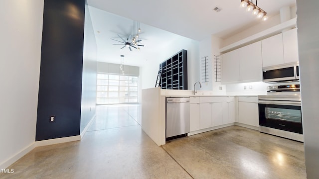 kitchen featuring baseboards, appliances with stainless steel finishes, light countertops, white cabinetry, and a sink