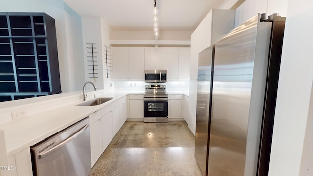 kitchen featuring appliances with stainless steel finishes, light countertops, a sink, and white cabinetry