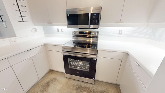 kitchen with tasteful backsplash, white cabinetry, stainless steel appliances, and light countertops