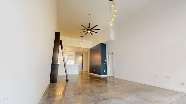 unfurnished room with baseboards, a high ceiling, and finished concrete floors