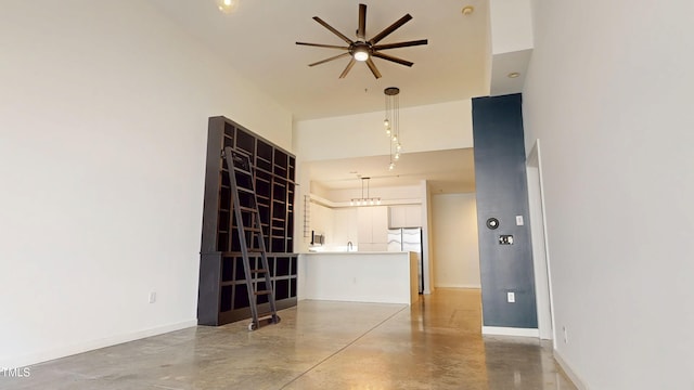 spare room featuring concrete floors, baseboards, and a ceiling fan