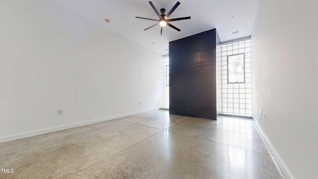 empty room with finished concrete floors, baseboards, and a ceiling fan