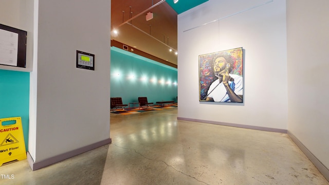 hall with finished concrete flooring and baseboards