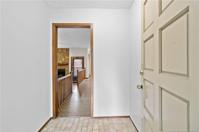 hall with a textured ceiling and light wood-type flooring