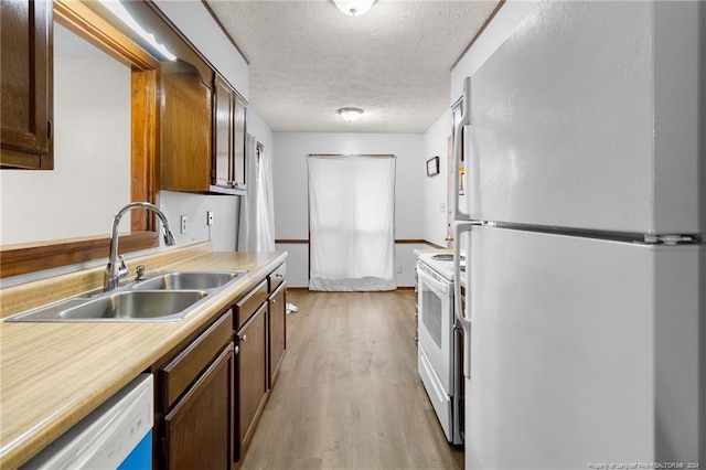 kitchen featuring a textured ceiling, sink, light hardwood / wood-style floors, and white appliances