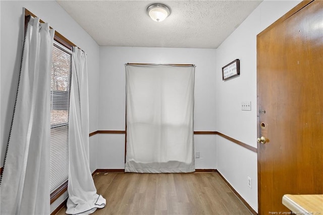 spare room with light wood-type flooring and a textured ceiling