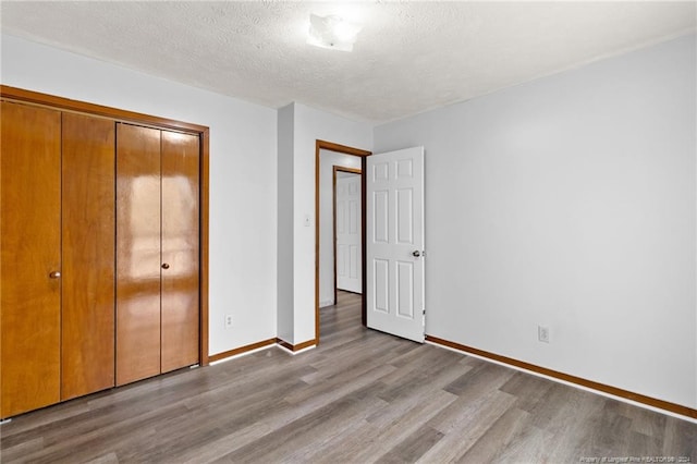 unfurnished bedroom featuring a textured ceiling, light wood-type flooring, and a closet