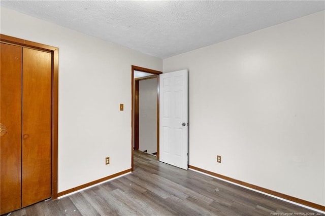 unfurnished bedroom with a closet, a textured ceiling, and hardwood / wood-style flooring