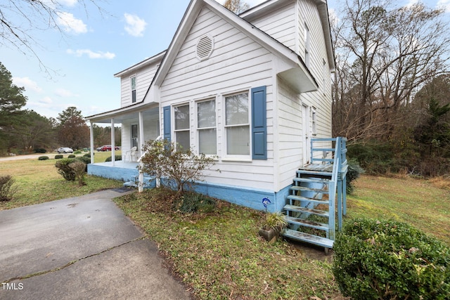 view of property exterior with covered porch and a yard