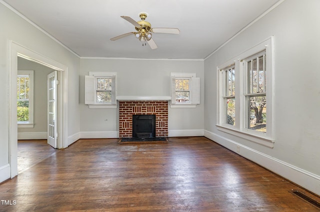 unfurnished living room featuring a wealth of natural light, ceiling fan, crown molding, and a brick fireplace