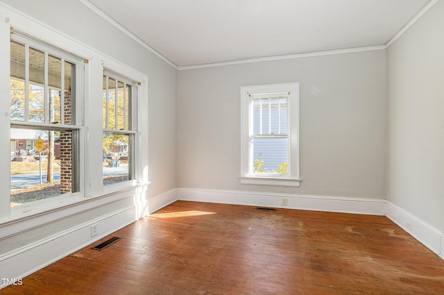 empty room featuring hardwood / wood-style floors, plenty of natural light, and ornamental molding