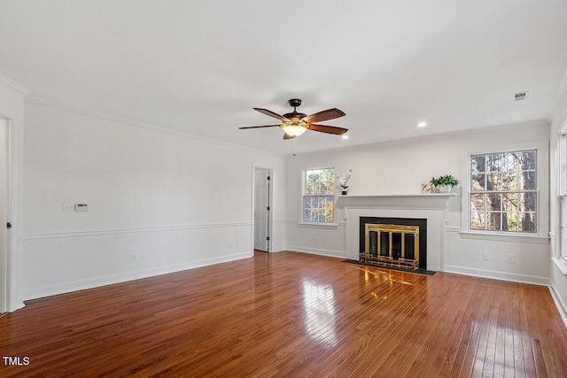 unfurnished living room featuring a wealth of natural light, wood-type flooring, and ornamental molding