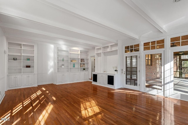 unfurnished living room featuring built in features, beamed ceiling, and wood-type flooring