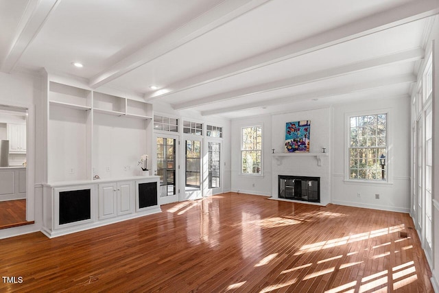 unfurnished living room with beam ceiling, a fireplace, hardwood / wood-style floors, and a healthy amount of sunlight