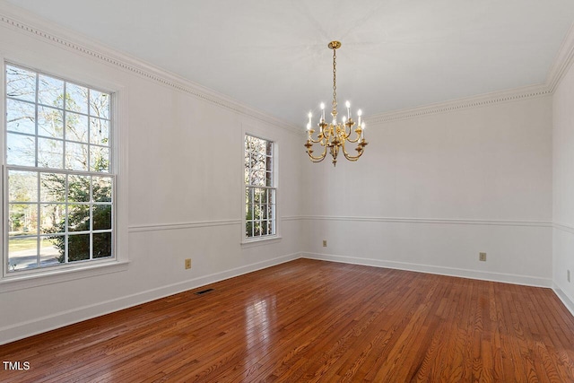 unfurnished room featuring hardwood / wood-style flooring, an inviting chandelier, and crown molding