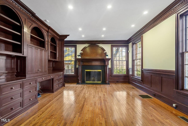 unfurnished living room with crown molding, light hardwood / wood-style flooring, and built in desk