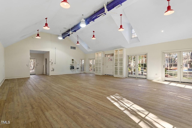 unfurnished living room with french doors, high vaulted ceiling, and hardwood / wood-style floors