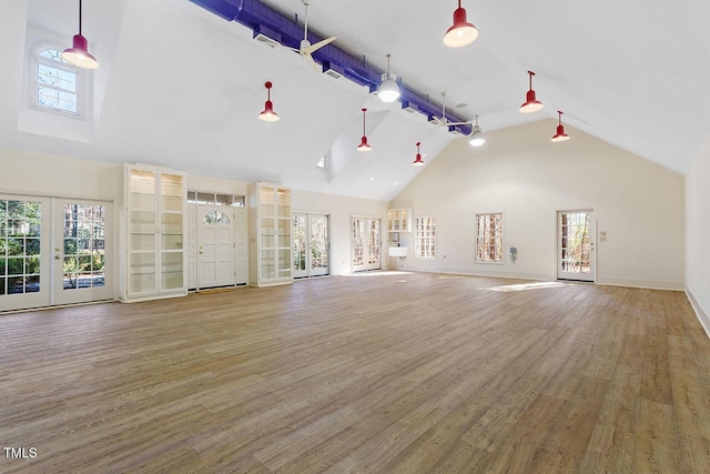 unfurnished living room featuring wood-type flooring, high vaulted ceiling, and french doors