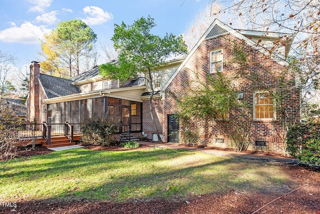 rear view of house with a lawn, a wooden deck, and a sunroom