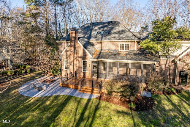 rear view of house with a sunroom, a deck, and a lawn