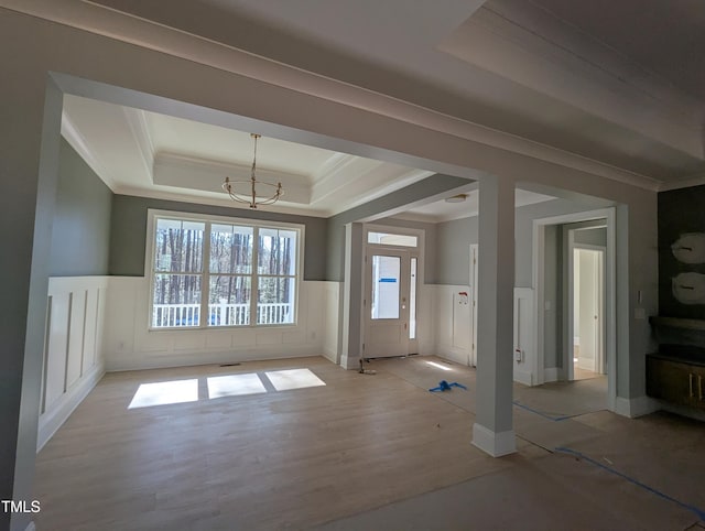 interior space with a tray ceiling, light hardwood / wood-style flooring, and crown molding