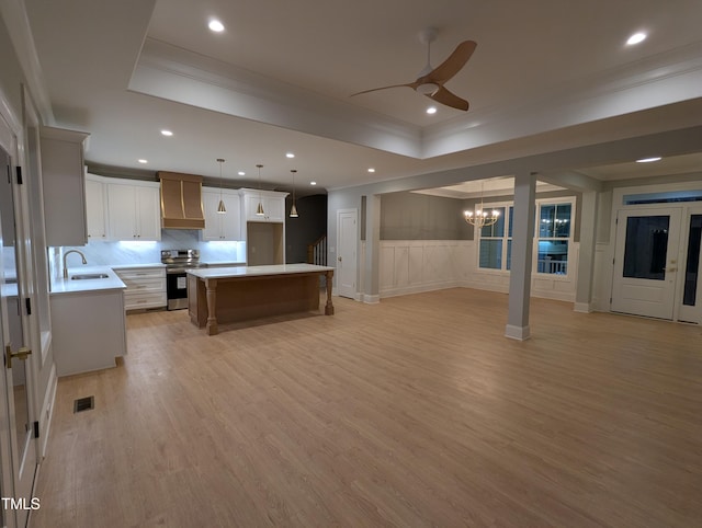 kitchen featuring white cabinetry, a center island, electric stove, wall chimney range hood, and pendant lighting