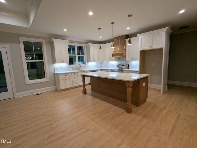 kitchen featuring white cabinets, stainless steel range with electric cooktop, hanging light fixtures, and a center island