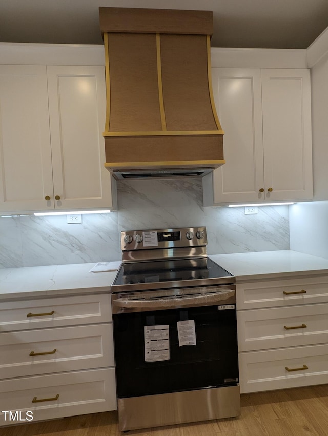 kitchen with white cabinetry, electric range, custom exhaust hood, and backsplash