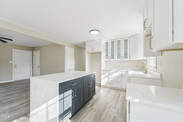 kitchen with ceiling fan, sink, light hardwood / wood-style flooring, a center island, and white cabinetry