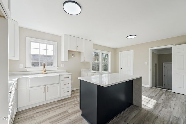 kitchen with white cabinetry, a kitchen island, light hardwood / wood-style floors, and sink