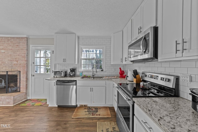 kitchen featuring appliances with stainless steel finishes, a wealth of natural light, sink, white cabinets, and dark hardwood / wood-style flooring