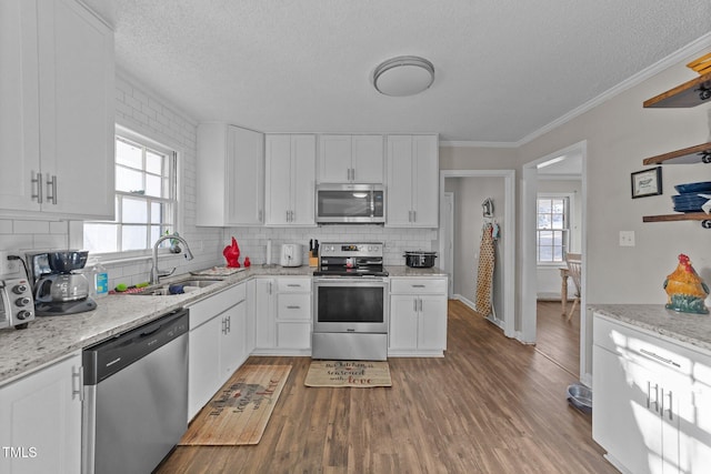 kitchen with sink, appliances with stainless steel finishes, hardwood / wood-style floors, plenty of natural light, and white cabinets