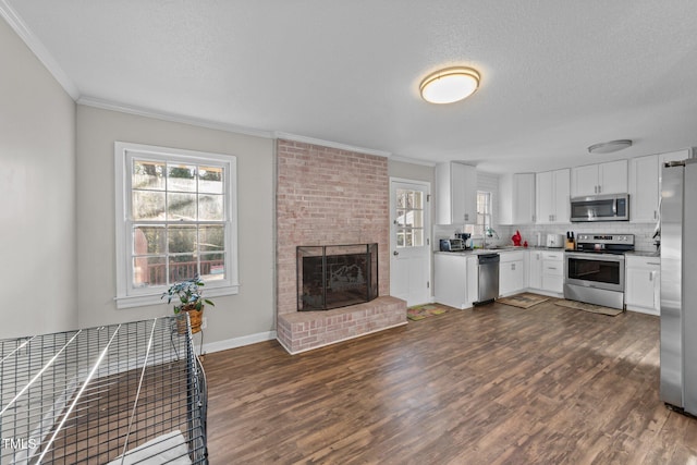 kitchen with dark wood-type flooring, stainless steel appliances, a fireplace, and white cabinets